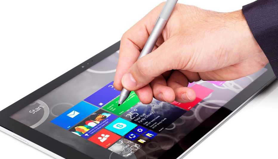 Person using Microsoft Surface Pro 3 tablet computer closeup of a hand with a stylus pen isolated on white background