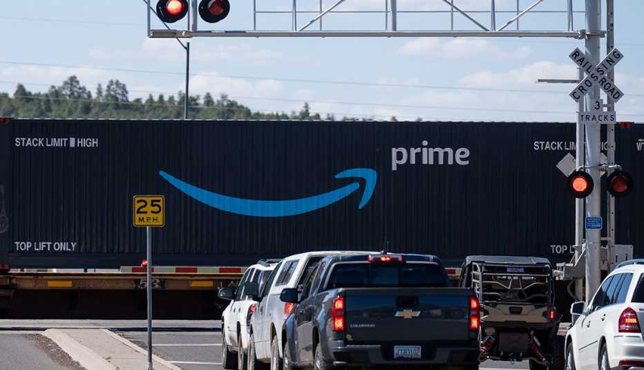 a railcar with an amazon prime logo blocks traffic while rolling through a town