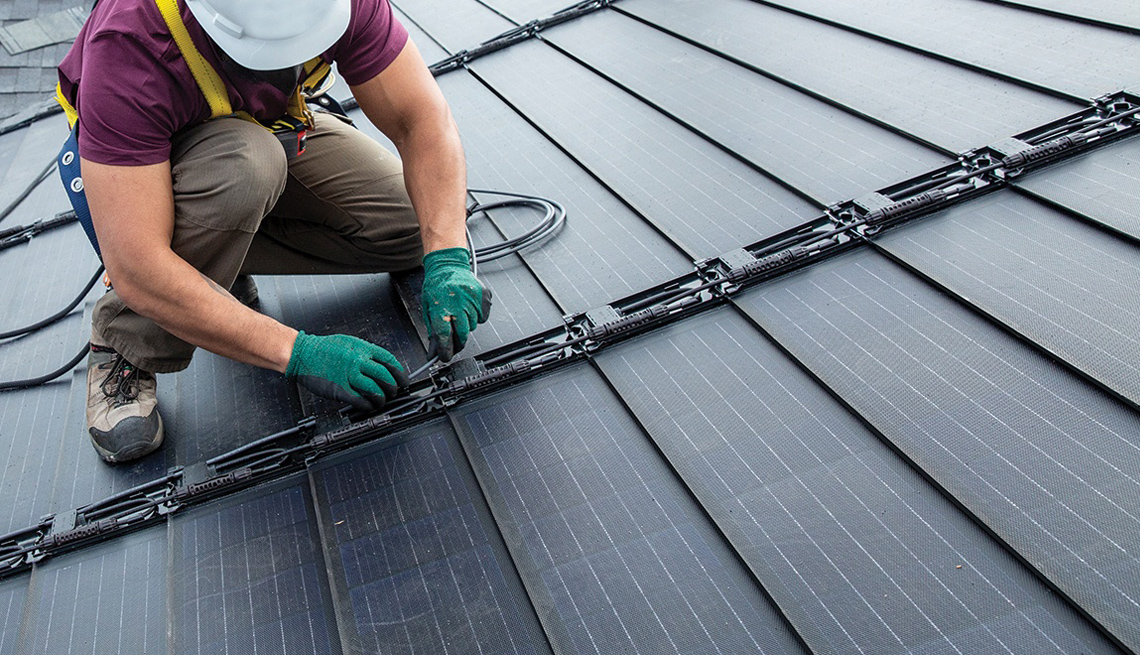 a man on a rooftop installing timberline solar shingles