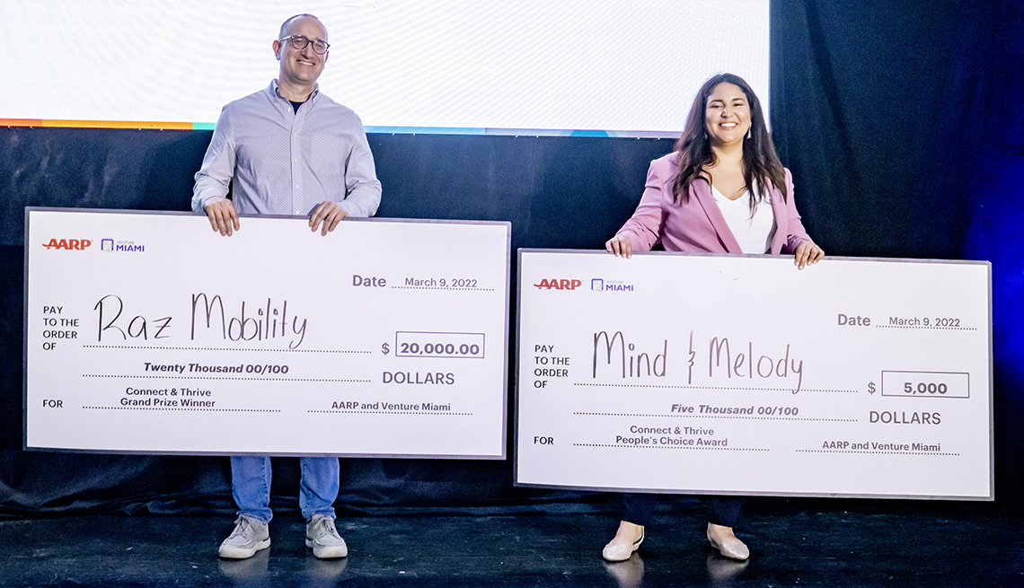 robert felgar of raz mobility and christina rodriguez of mind and melody stand on stage with their winning checks at the connect and thrive pitch competition in miami in twenty twenty one 