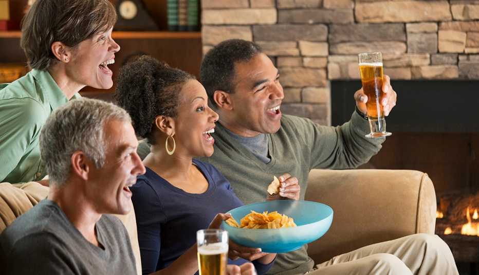 two couples drink beer and eat chips while watching a sporting event