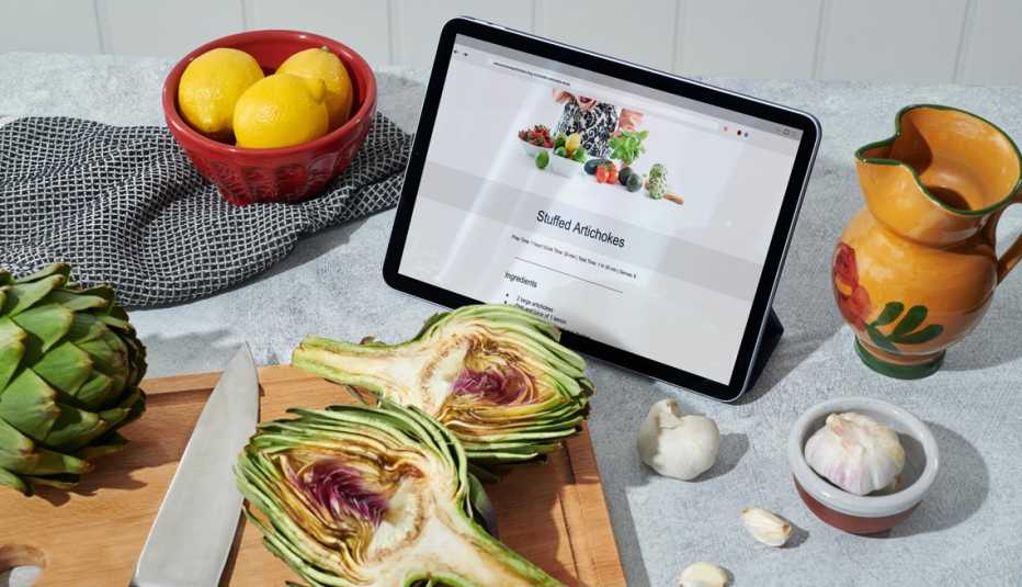 a tablet showing a recipe in front of artichokes and other ingredients