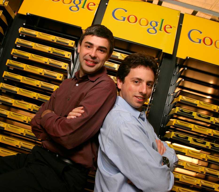 google co-founders larry page and sergey brin posing in front of signs