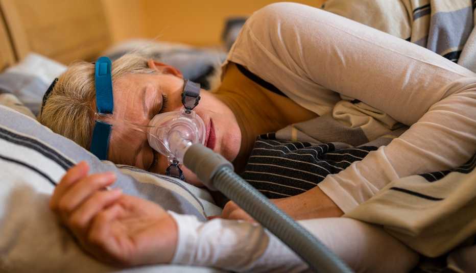 close up of a woman using Continuous positive airway pressure (CPAP) machine to stop choking and snoring from obstructive sleep apnea
