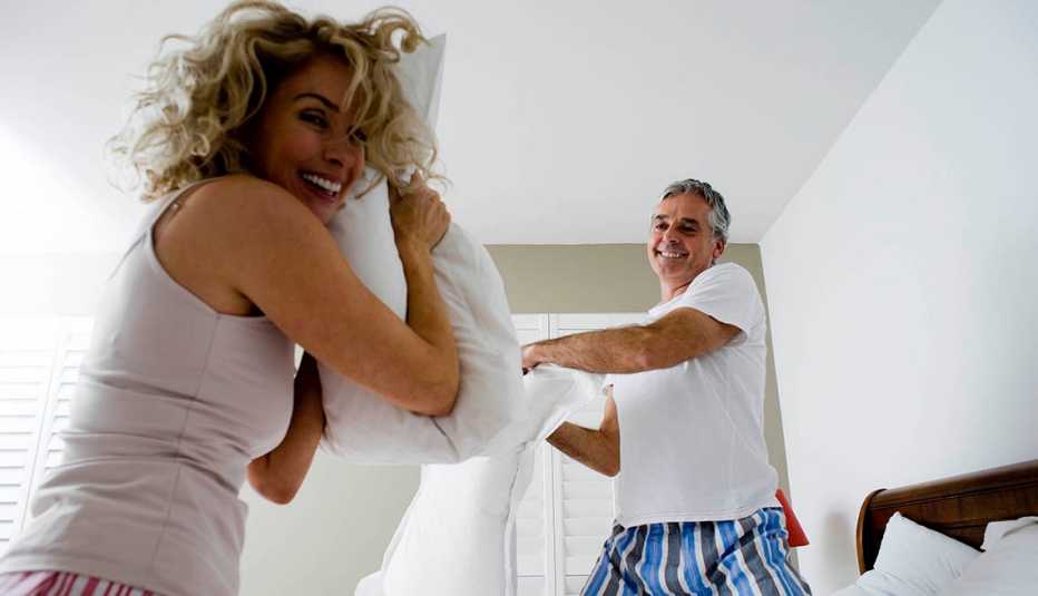 A couple having a fun pillow fight in bed