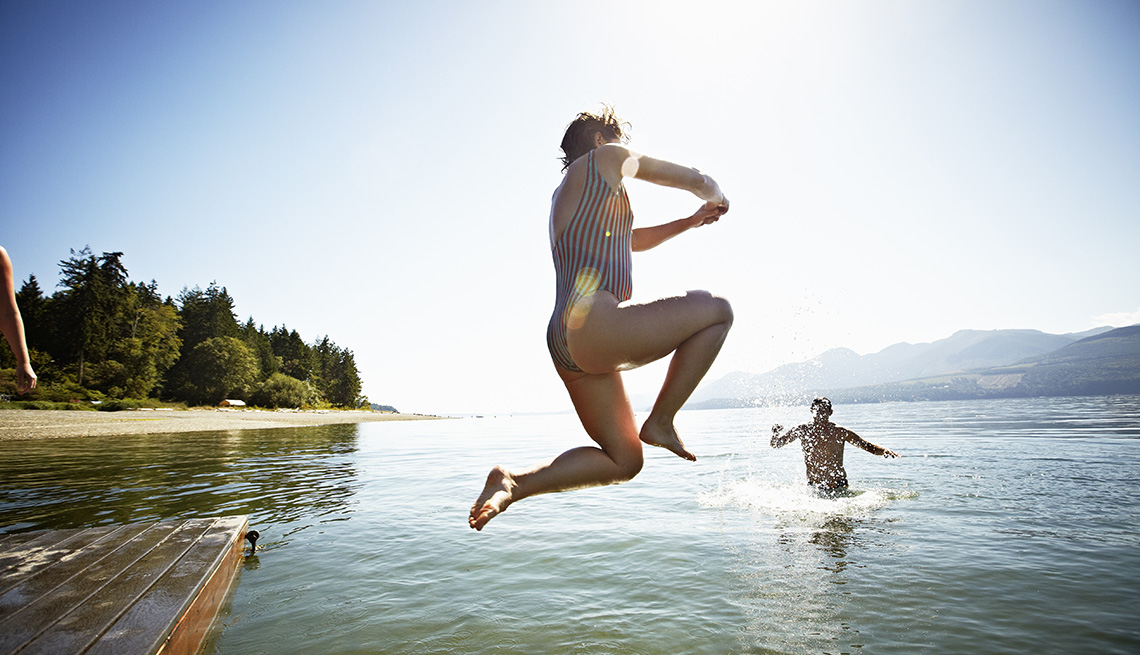 Woman Jumping Into Lake In Midair With Her Husband Or Partner Standing In Lake, AARP Home And Family, How To Support Your Entrepreneurial Spouse