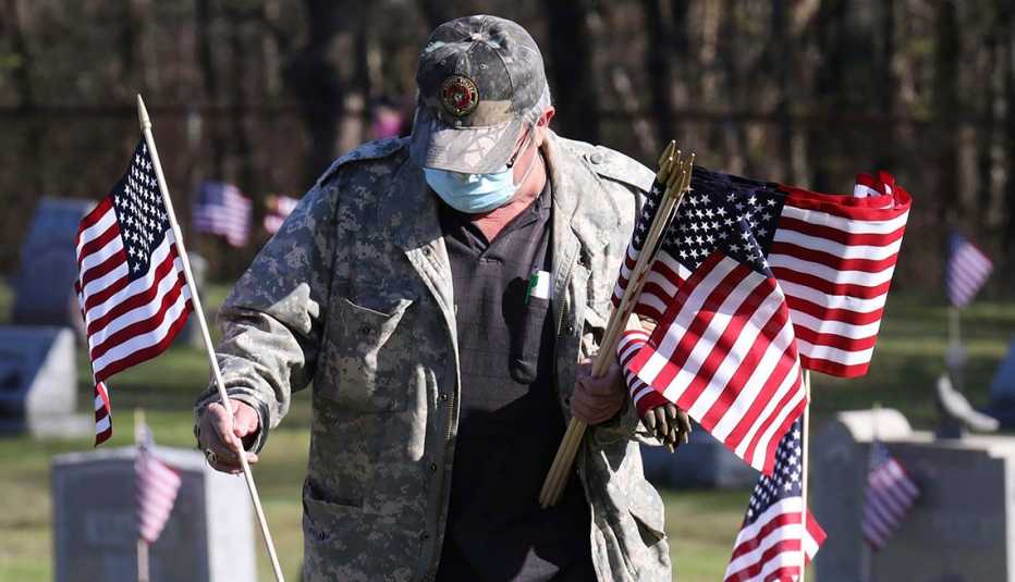 A man wearing a mask places flags on graves