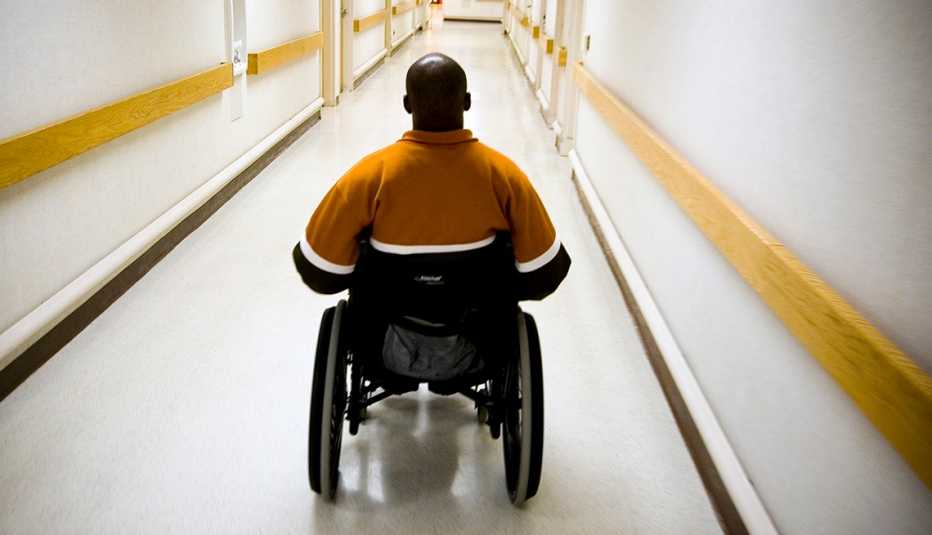 A man in a wheelchair goes down a hall way