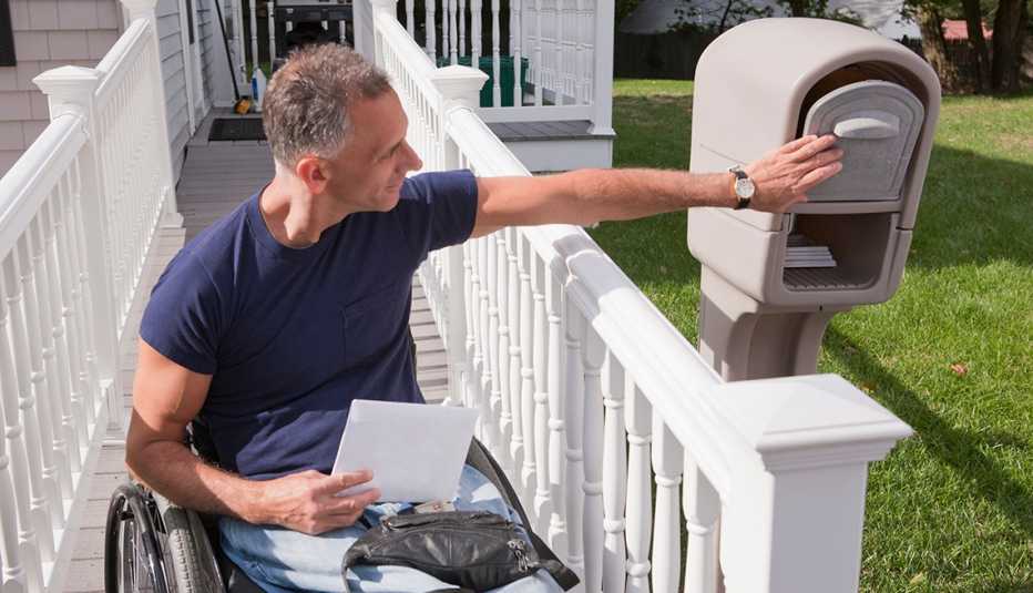 A man in a wheelchair is getting mail out of his mailbox