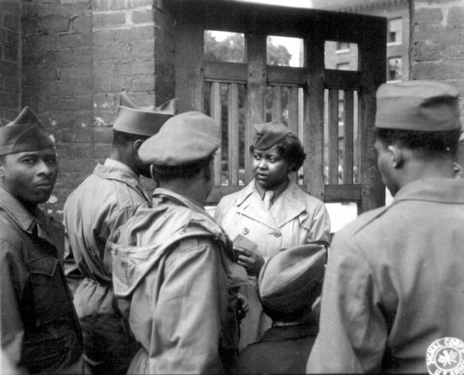 A group of African American soldiers are talking outside of a door during World War Two
