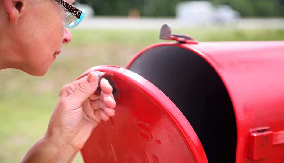 A person is opening a red mail box