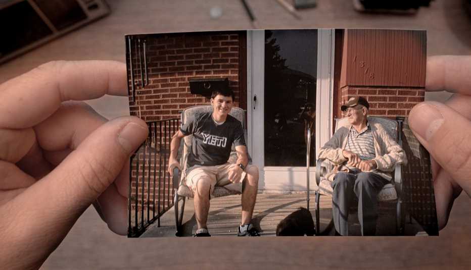 hands holding a photo of two people in chairs