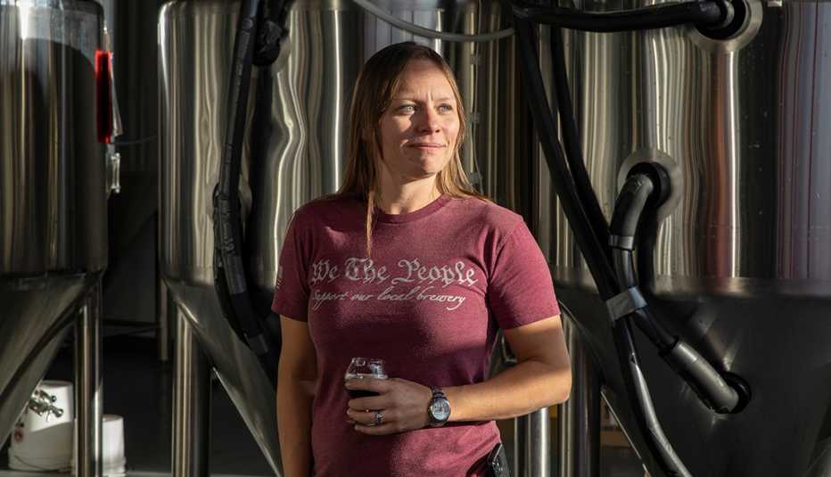 a woman stands with a drink in her hands at a distillery