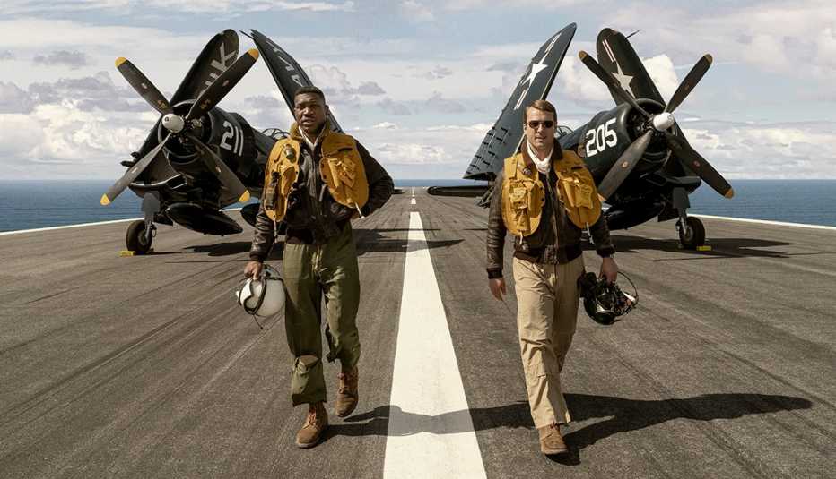 two men are walking with planes in the background