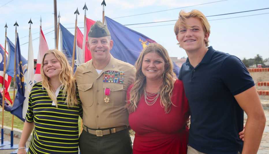 a family of four stands together with flags in the background