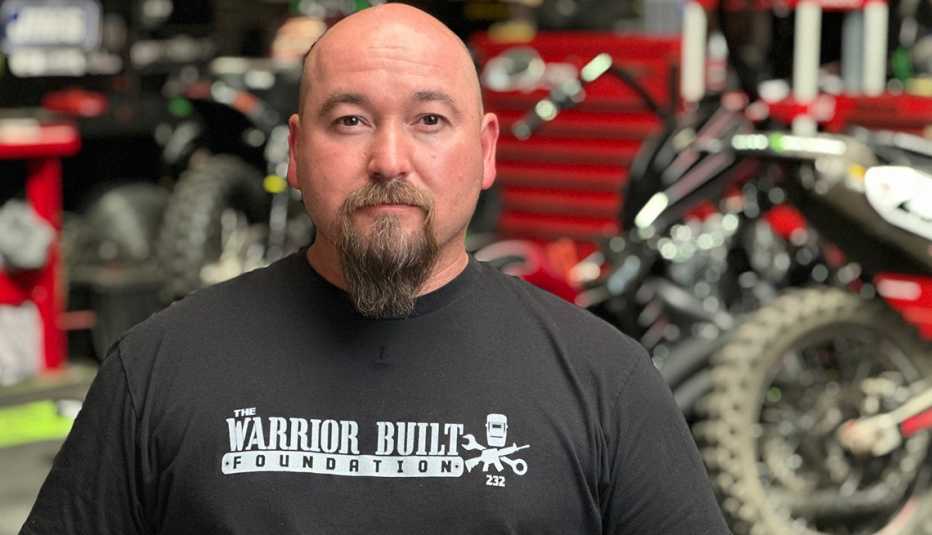 Nick Hamm stands in a garage wearing a t-shirt from The Warrior Built Foundation.