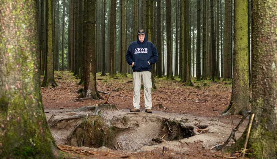 a man standing in the woods next to a giant hole from a battle