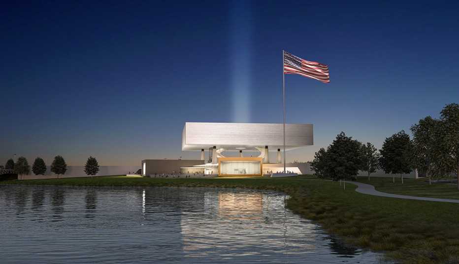 a photo rendering shows the future national medal of honor museum at night. an american flag flies next to the museum, which is on the waterfront.