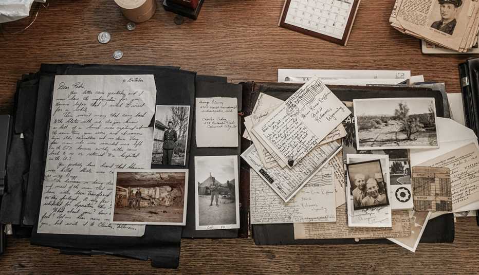 a pile of old letters, postcards and photographs are displayed on a wood table