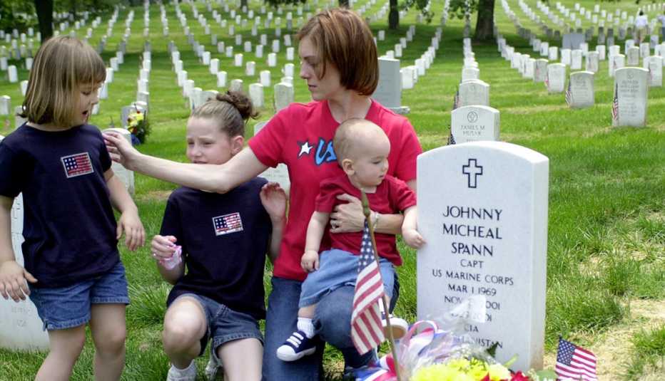 a mother and her kids next to the grave of their father