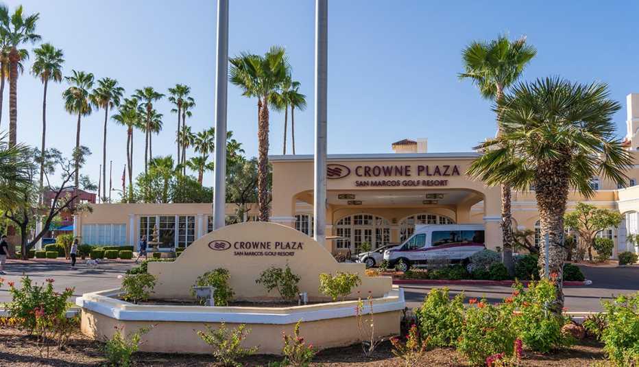 signs point to the entrance of the crowne plaza san marcos golf resort with palm trees in the background