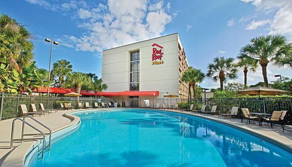 a blue pool is pictured in front of a red roof inn building