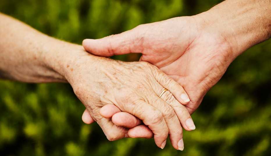 two people hold hands in front of a green background.