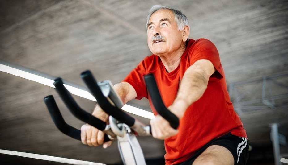 Healthy senior man in gym cycling on exercising bicycle
