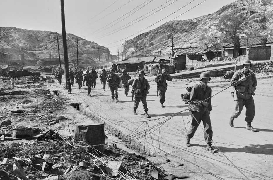 historical photo from nineteen fifty one korean war showing members of a united nations infantry patrol walking on a deserted street outside of seoul