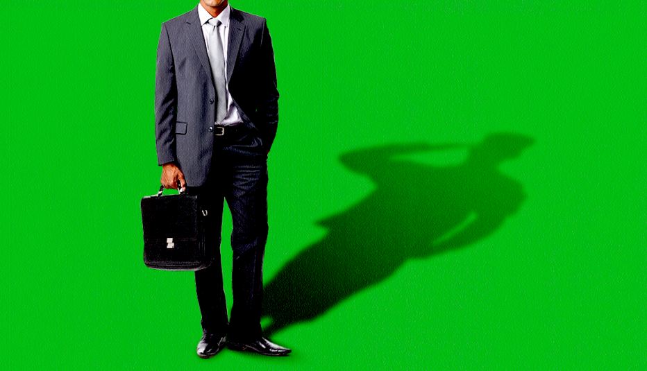 a man in a suit holds a briefcase in front of a green background. his shadow is of a military member saluting
