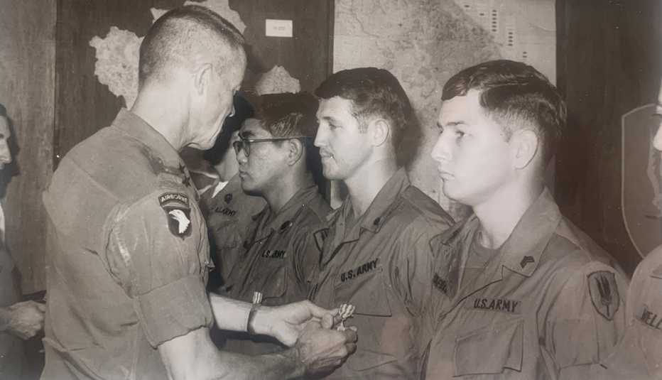 a black and white photo shows mike lowry getting a silver star pinned on his uniform