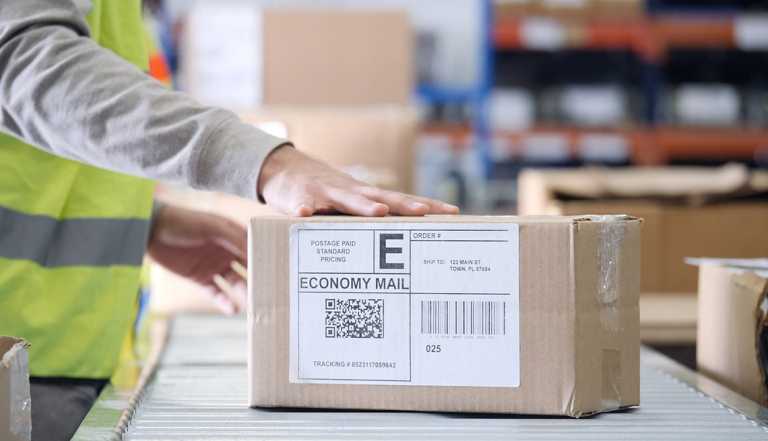 man handles a priority box on an assembly line in a mail distribution center