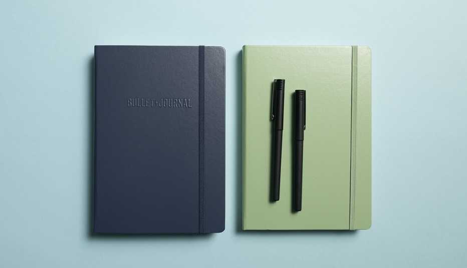 a black and green notebook with two pens on a blue background