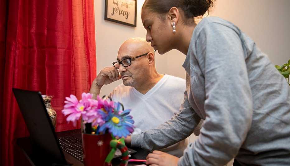 a teenage girl helps her grandfather on the computer in their home