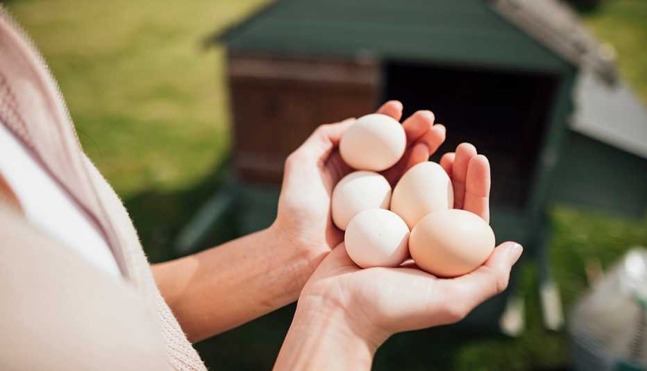 A pair of hands holding five fresh eggs