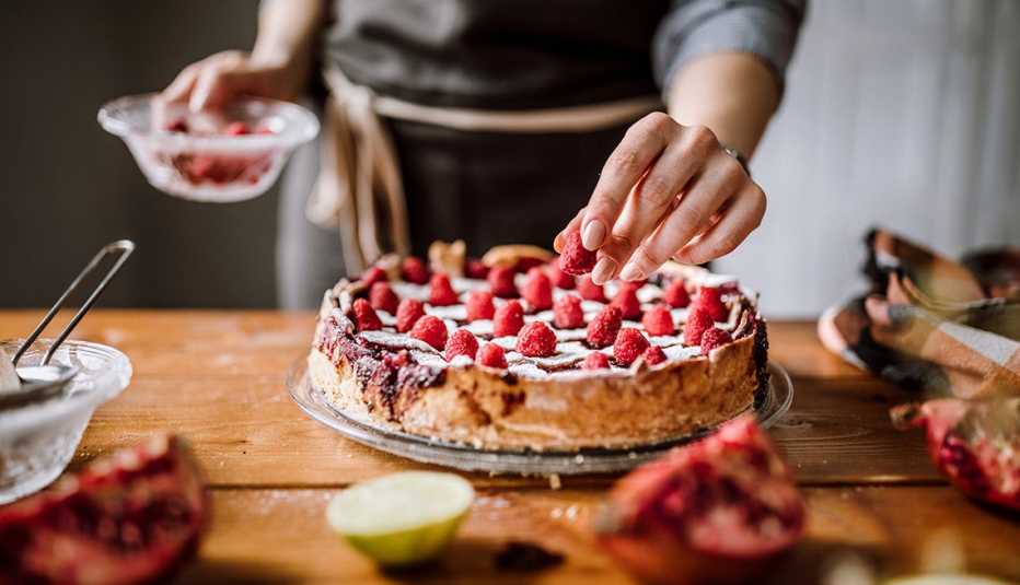Woman Putting Raspberries To American Blackberry Pie, While It Is In  Mold