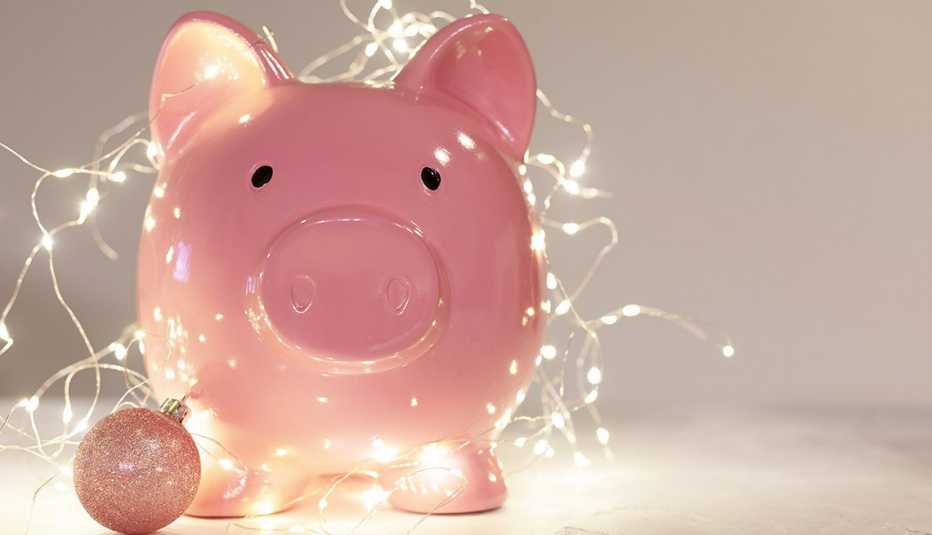 pink piggy bank with pink christmas bauble and christmas lights on white background