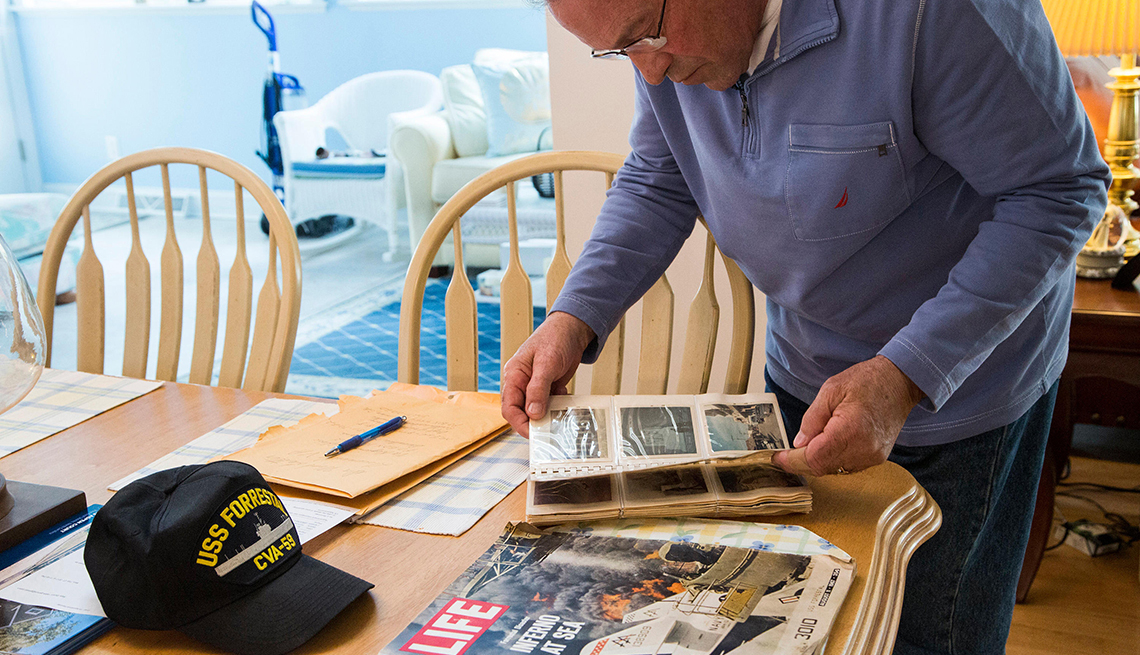 Sam Grenco is a Blue Water Navy Vietnam veteran looking through an old photo album on a table