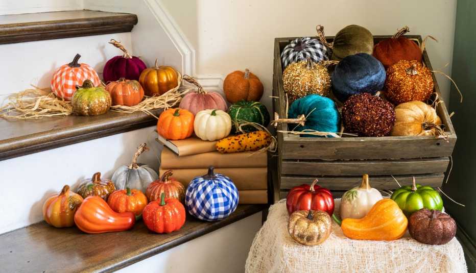 an assortment of colorful pumpkins in a basket and on the stairs