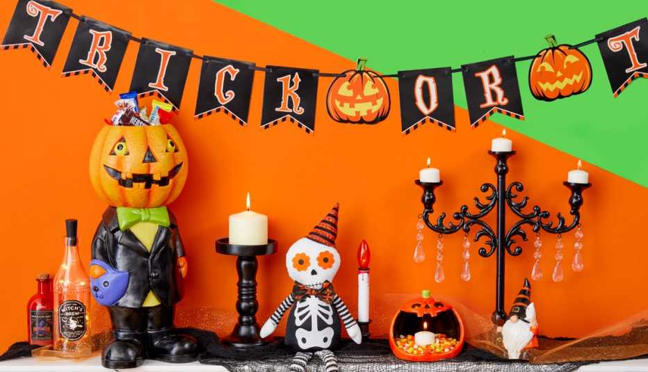 a mantle decorated for halloween with a trick or treat banner and candles and skeletons