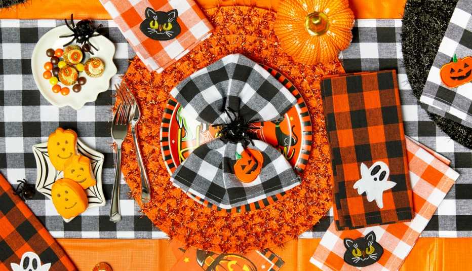 a tabletop decorated for halloween with pumpkins and candy and spiders and cats