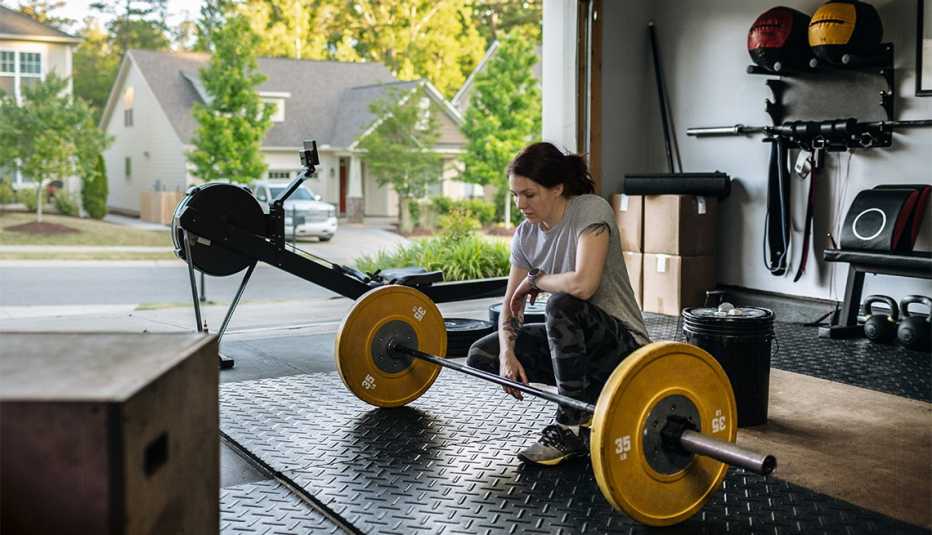 woman sitting in front of the barbell in her home garage gym