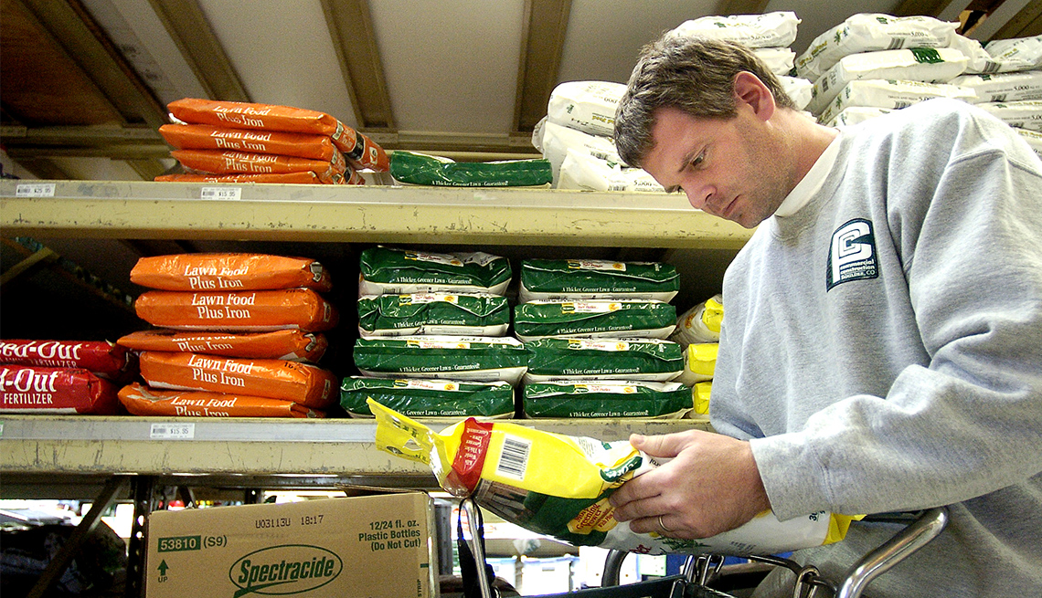 man reads information on the back of a bag of lawn fertilizer