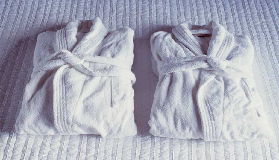 2 hotel bathrobes on a bed