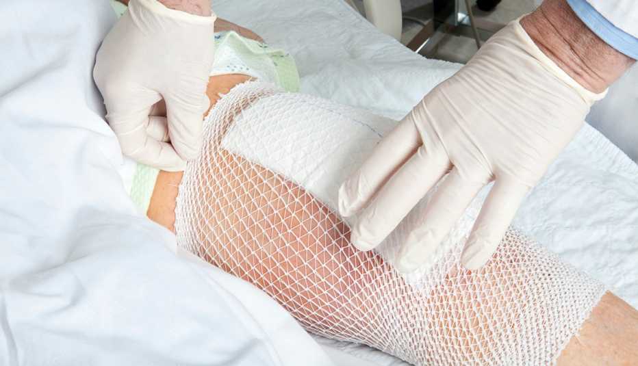 A doctor checking the bandage on a knee replacement patient