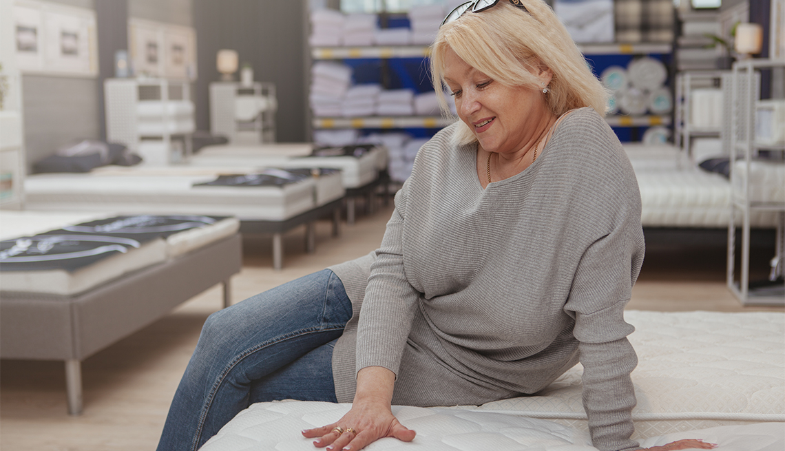 woman sitting on mattress at furniture store