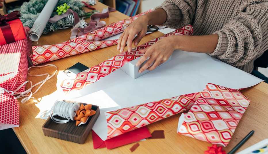 woman wrapping gifts with christmas themed wrapping paper