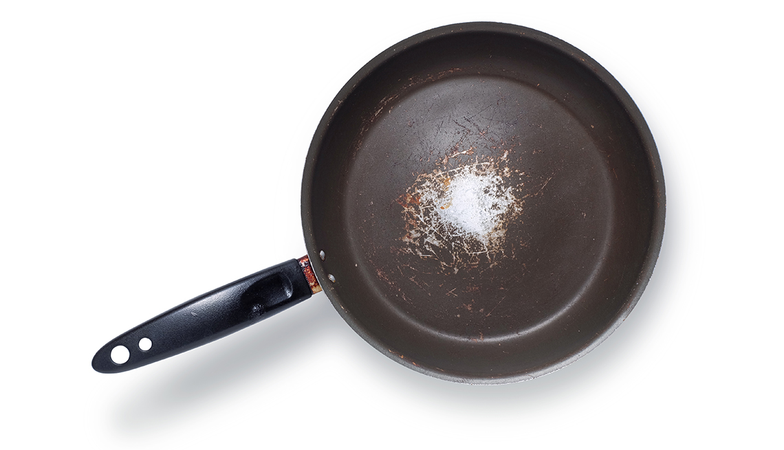 An old used frying pan showing scratches and cooking stains, isolated on white background with clipping path