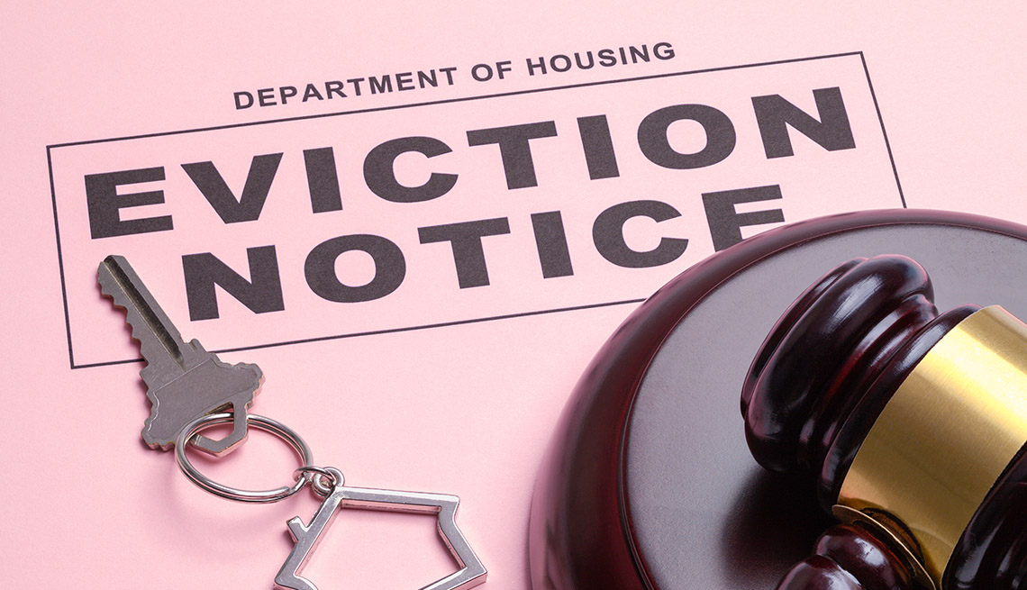 An eviction notice ruling printed on pink paper is displayed with a gavel and house keys