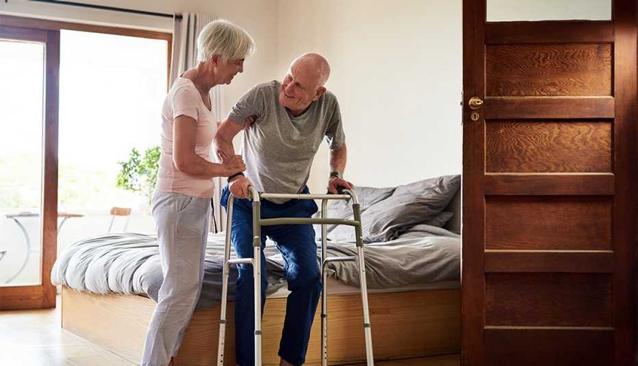 a woman helping her husband out of bed with his walker